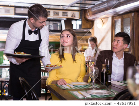 Frendly waiter is giving order for couple who is resting with white wine Frendly waiter is giving order for couple who is resting with white wine 48617951