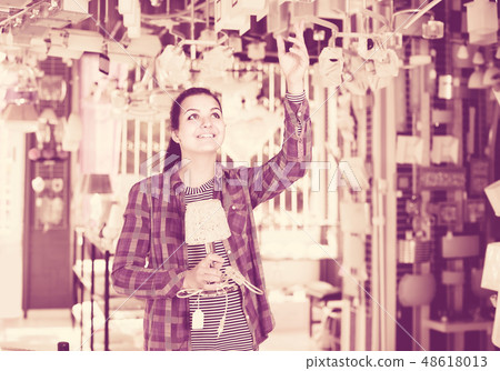 girl in lighter shop choosing modern glass chandelier for house interior 48618013