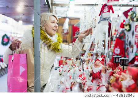 Mature woman choosing decorations at Christmas market Mature woman choosing decorations at Christmas market 48618043