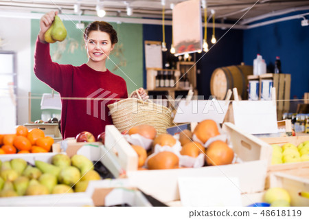Ordinary young girl choosing pear at market 48618119