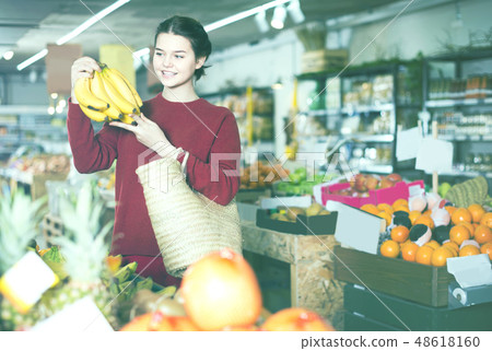 Portrait of brunette girl buying ripe bananas in supermarket 48618160