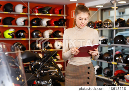Positive young woman in moto salon choosing motorcycle to buy Positive young woman in moto salon choosing motorcycle to buy 48618238