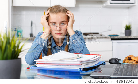Tired girl sitting among notebooks Tired girl sitting among notebooks 48618342