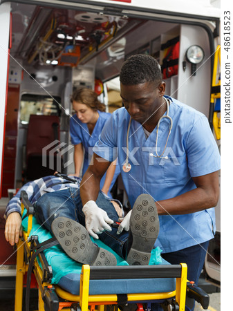 Ambulance team laying patient on stretcher Ambulance team laying patient on stretcher 48618523
