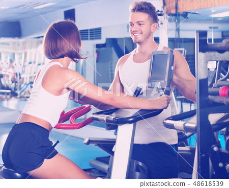 Woman and man using bicycle gym machinery together Woman and man using bicycle gym machinery together 48618539