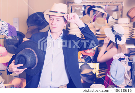 Portrait of cheerful male try on hat 48618616