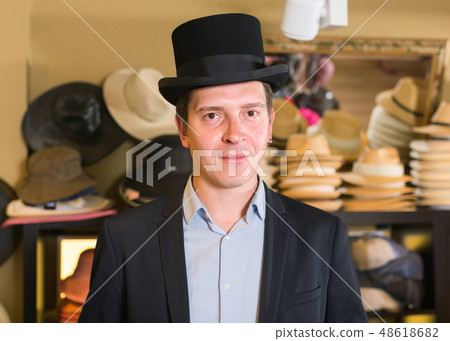 adult male shopping in botique and try on cylinder hat 48618682