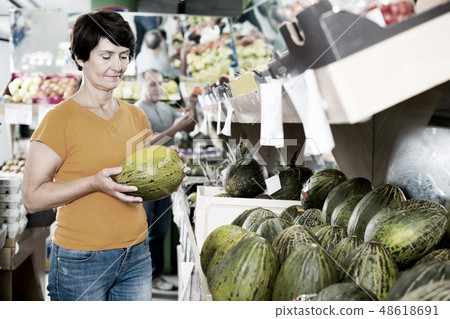 Female is choosing green melons 48618691