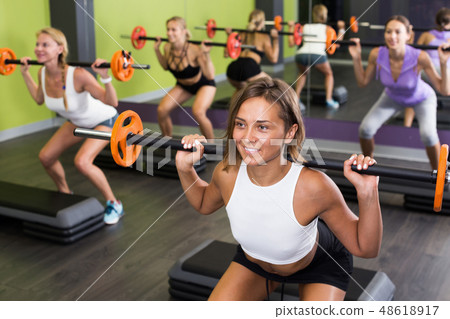Girls exercising with barbell workout at fitness center 48618917