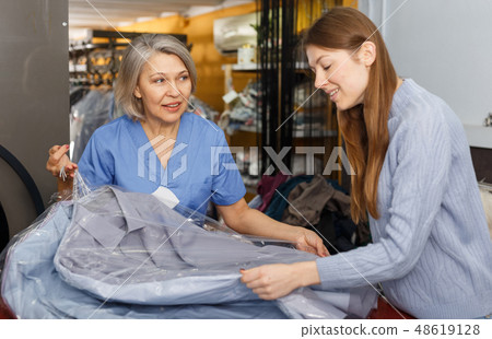 Worker giving woman her clean clothes 48619128