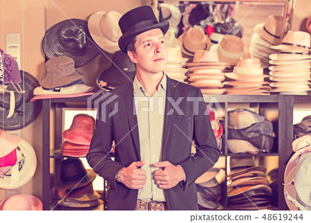 adult male shopping in botique and try on cylinder hat 48619244