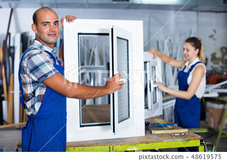 Confident man in workwear with finished window from pvc profile at workplace 48619575