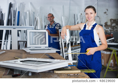 Craftswoman with plastic window frame and measuring tape Craftswoman with plastic window frame and measuring tape 48619600