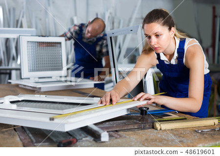 Workwoman is checking dimensions of finished plastic window usin Workwoman is checking dimensions of finished plastic window usin 48619601