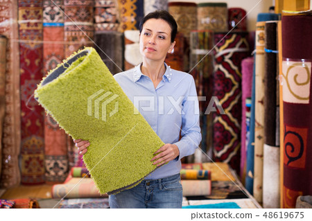 Cheerful woman customer shopping carpet in store Cheerful woman customer shopping carpet in store 48619675