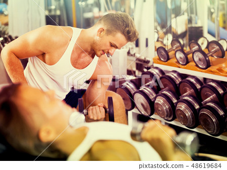 well trained man training hands using heavy weight dumbbells in 48619684