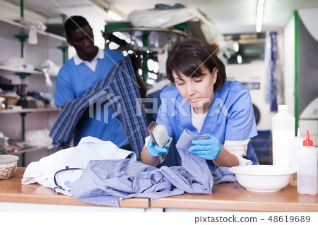 Woman dry cleaning clothes in laundry Woman dry cleaning clothes in laundry 48619689