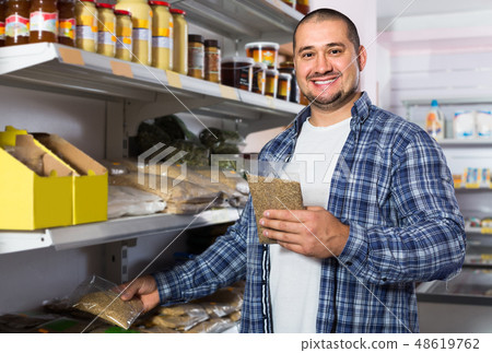 Male customer choosing nuts and grain in average food shop Male customer choosing nuts and grain in average food shop 48619762
