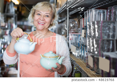 Positive female choosing kettle for drinking tea Positive female choosing kettle for drinking tea 48619768