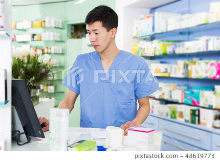 japanese specialist standing near table with cashbox in pharmacy 48619773