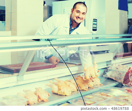 Male shop assistant selling kosher chicken at counter and smiling Male shop assistant selling kosher chicken at counter and smiling 48619788