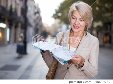 Adult woman 50-60 years old is walking with map in classic dress 48619789