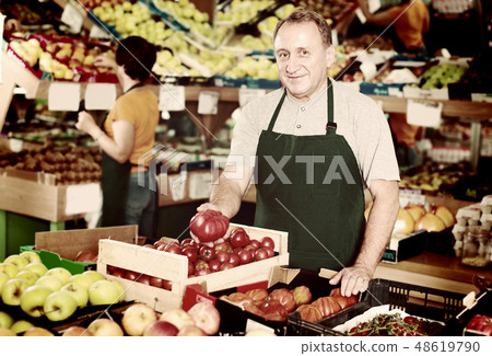 Smiling male seller is demonstrating tomatos Smiling male seller is demonstrating tomatos 48619790