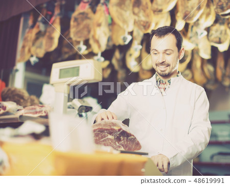Positive male assistant weighing piece of meat Positive male assistant weighing piece of meat 48619991