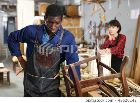 Craftsman restoring old chair in studio Craftsman restoring old chair in studio 48620142