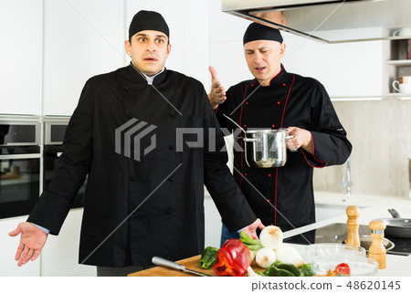 Men chefs in black uniform having conflict on kitchen Men chefs in black uniform having conflict on kitchen 48620145