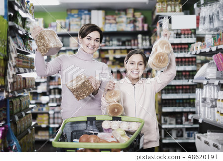 cheerful woman with daughter choosing bread in supermarket 48620191