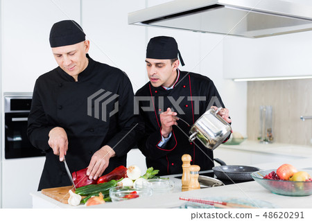 Men professionals are cooking salad in the kitchen Men professionals are cooking salad in the kitchen 48620291