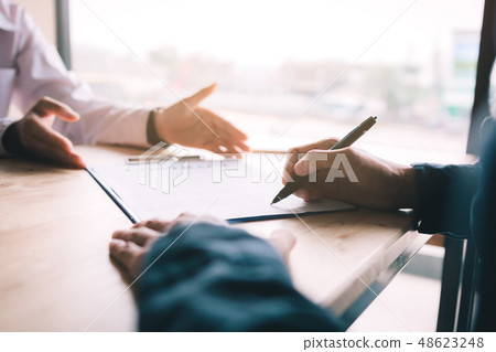 Real estate contract on desk with client signing Real estate contract on desk with client signing 48623248