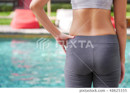 slim woman in yoga sportswear standing beside pool slim woman in yoga sportswear standing beside pool 48625335