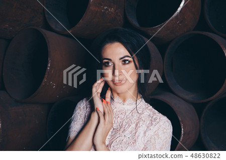 beautiful girl in a light dress among metal pipes 48630822