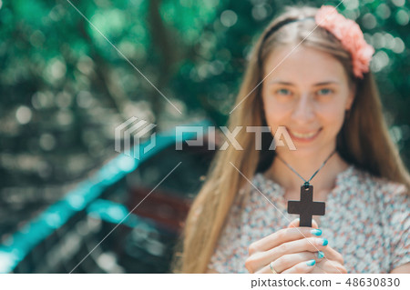 cross in hands of a girl close-up, woman blurred cross in hands of a girl close-up, woman blurred 48630830