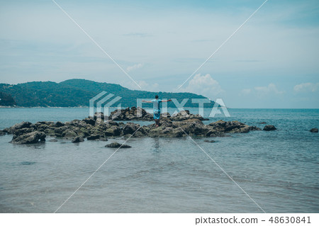 man on rock looking into the distance against sea 48630841