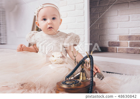 little girl in a white dress sitting by fireplace little girl in a white dress sitting by fireplace 48630842