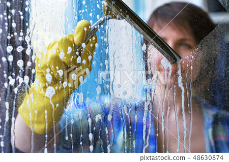 A girl washes windows at home. A girl washes windows at home. 48630874