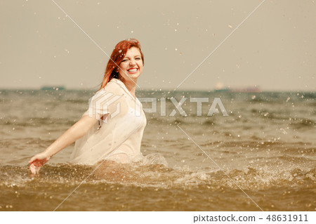 Redhead woman playing in water during summertime 48631911