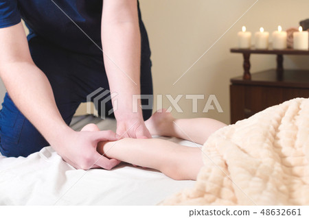 Close-up of male chiropractor hands massaging calves of a small patient. A little boy at the 48632661