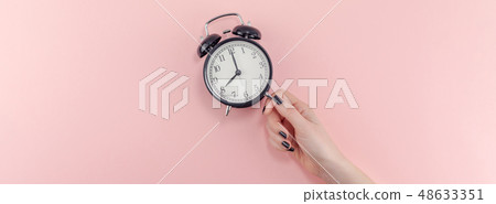Female hand with alarm clock. Morning concept Female hand with alarm clock. Morning concept 48633351