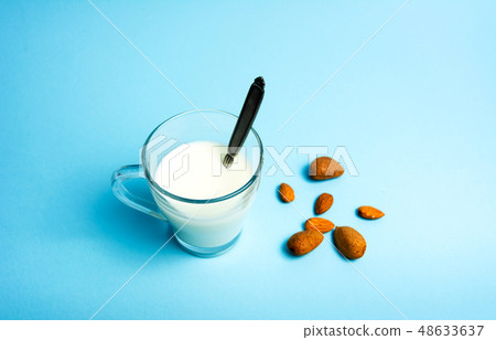 Almond milk in a glass against blue background Almond milk in a glass against blue background 48633637