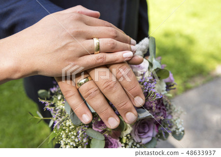 Hands of bride and groom with flower bouquet Hands of bride and groom with flower bouquet 48633937