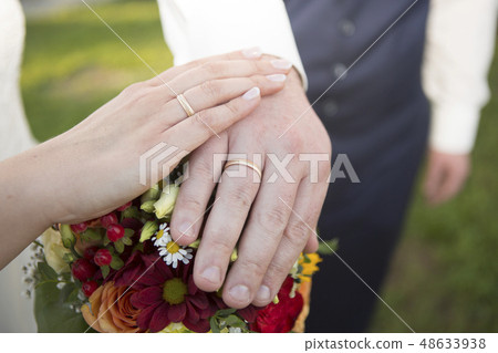 Hands of bride and groom with flower bouquet Hands of bride and groom with flower bouquet 48633938