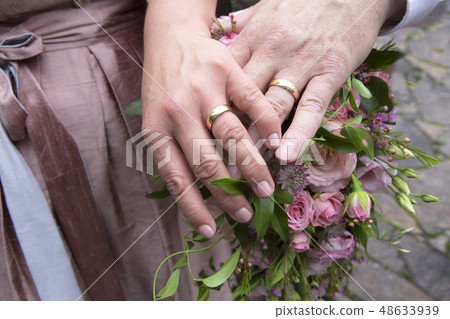 Hands of bride and groom with flower bouquet Hands of bride and groom with flower bouquet 48633939