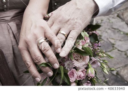 Hands of bride and groom with flower bouquet Hands of bride and groom with flower bouquet 48633940