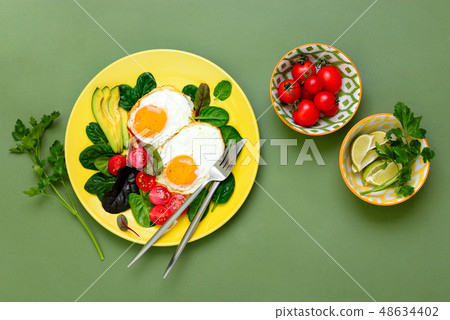 Fried eggs with spinach tomatoes and greens 48634402