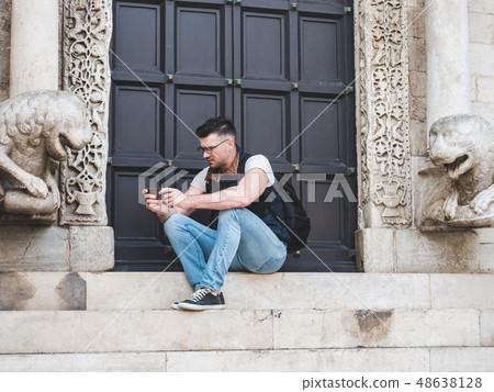 Attractive man with a phone, sitting on the street 48638128