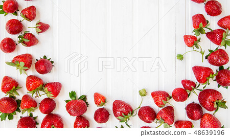 Ripe red strawberries scattered on a white wooden Ripe red strawberries scattered on a white wooden 48639196